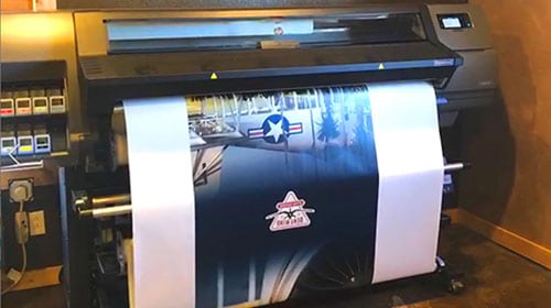 A photo of our large format vinyl printer printing a custom vinyl wrap for a vending machine.