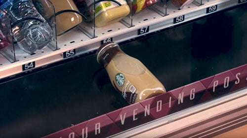 A photo of a glass drink bottle being safely lowered down by an elevator in one of our custom vending machines.